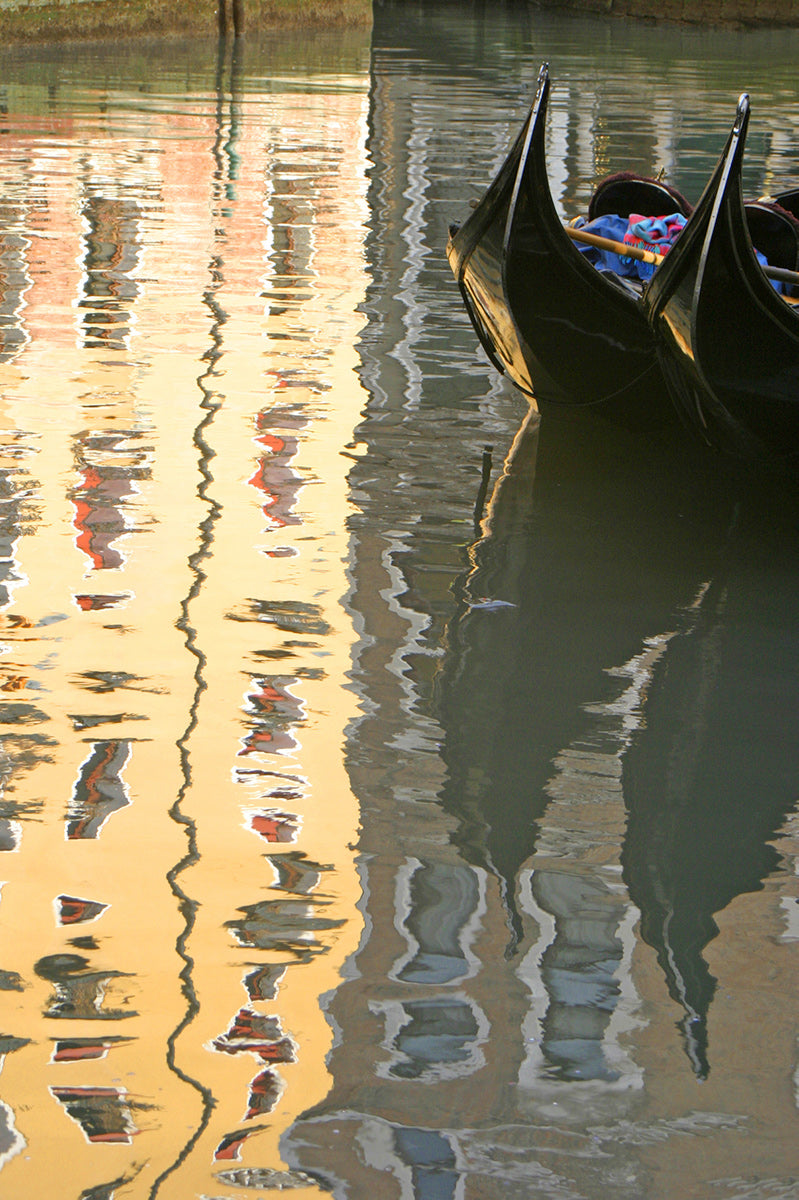Bright hotel reflected on the canal in Venice with 2 Gondolas moored  and reflected in the water 
