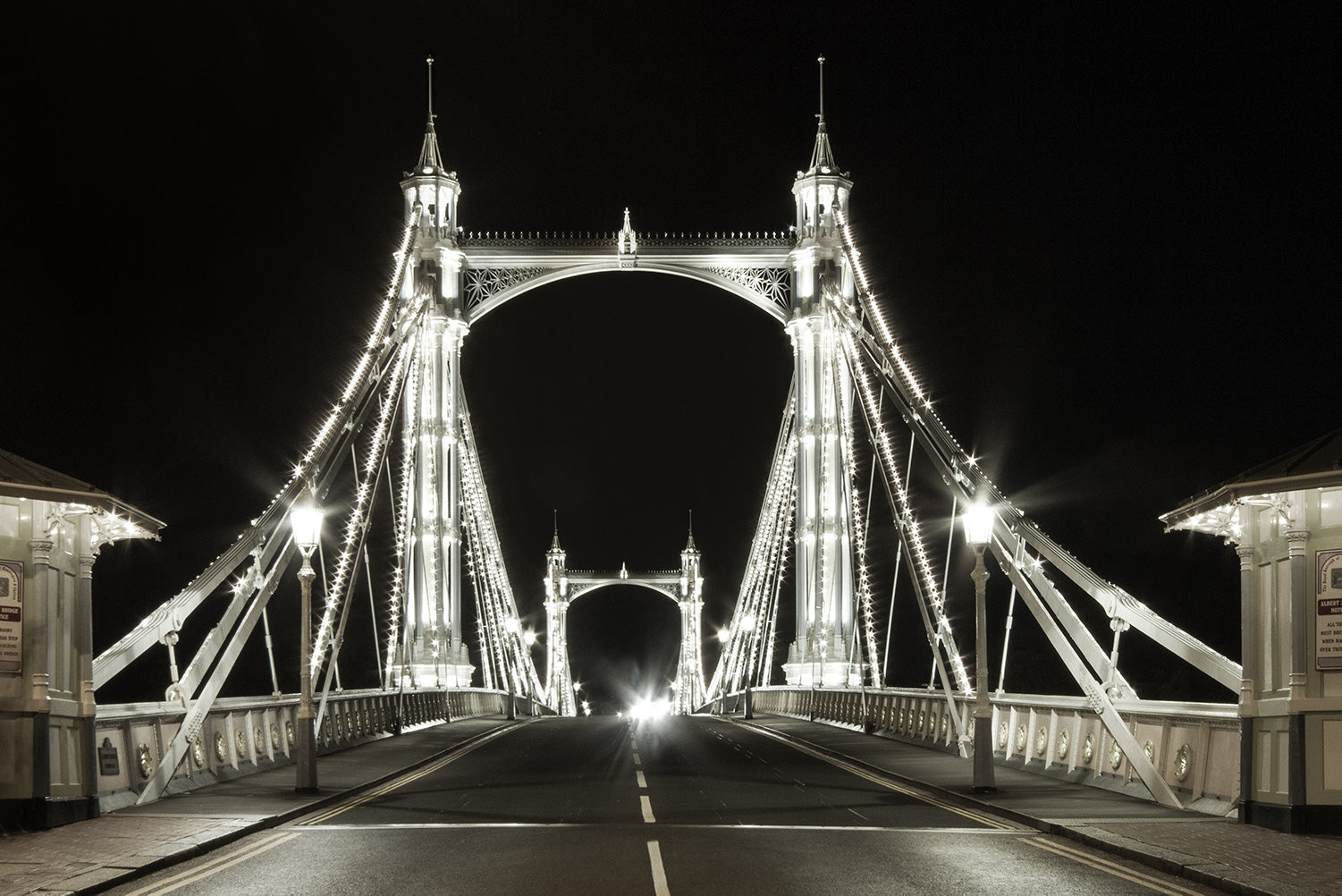 Black and white view of the fairy tale like Victorian Albert Bridge in London, lit up at night by 4000 LED lights.