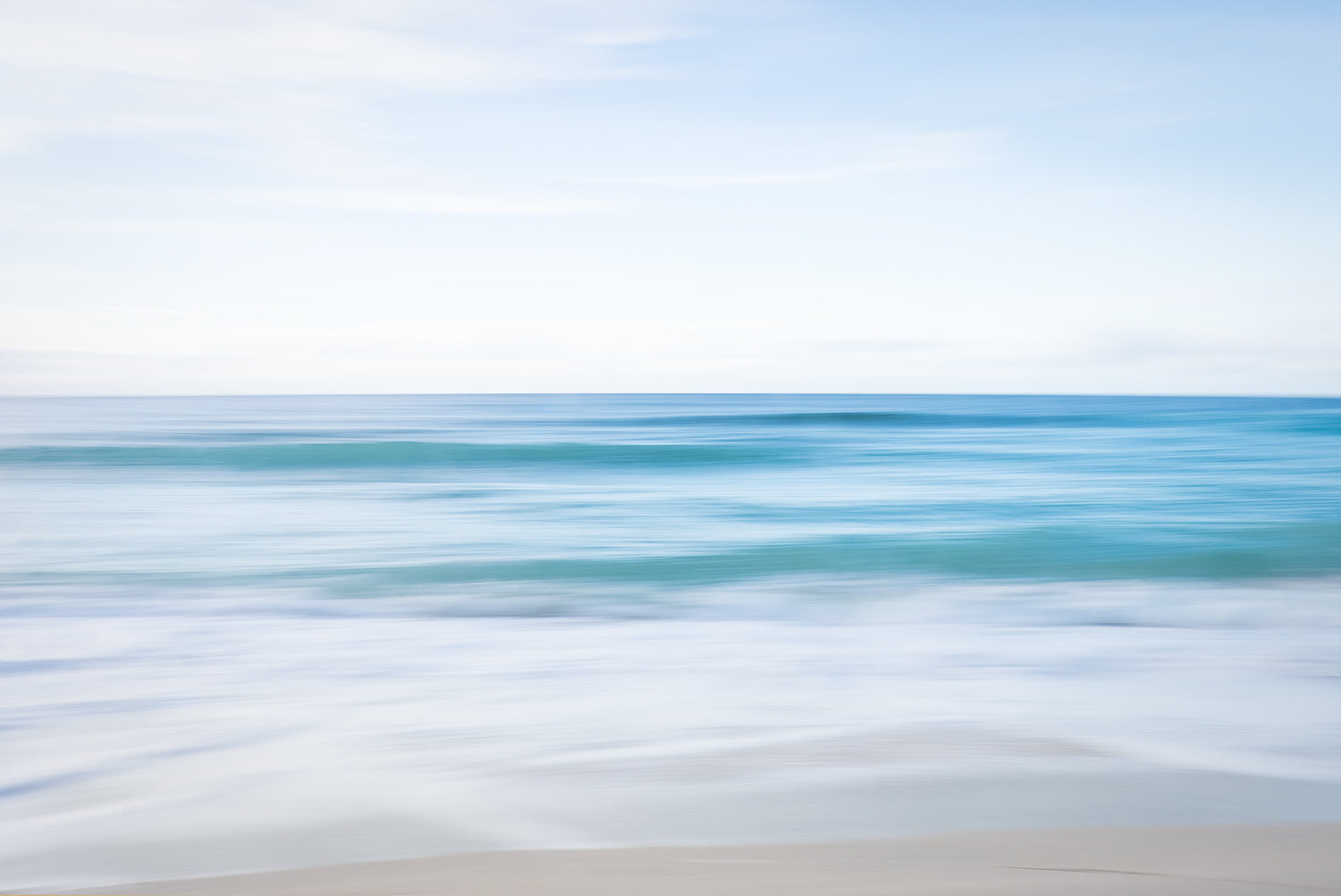A sea at St Ives, Cornwall on an early evening in September. The waves from the light blue sea gently caress the sandy beach creating a calming effect.