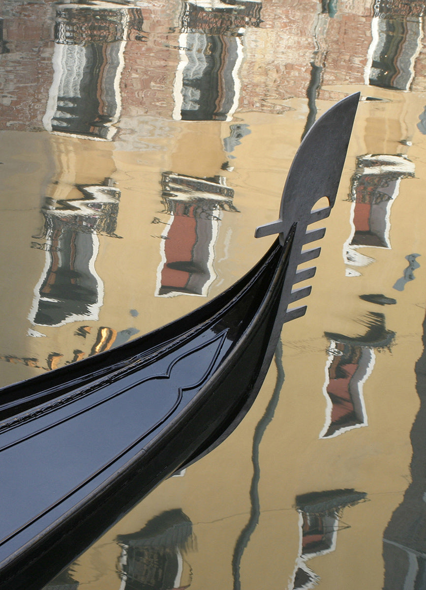 A moored gondola on the canal in front of a reflection of a hotel in the Bacino Orseolo, near St Mark's Square, Venice.